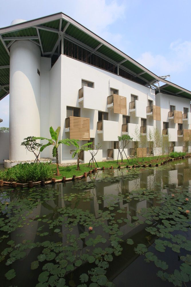 the building is white and has lots of green plants on it's front lawn