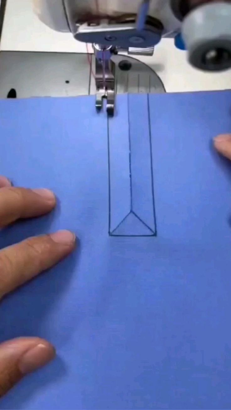 someone is using a sewing machine to sew something on a piece of blue paper