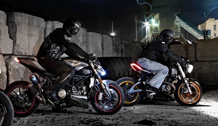 two motorcyclists are sitting on their bikes in the dark