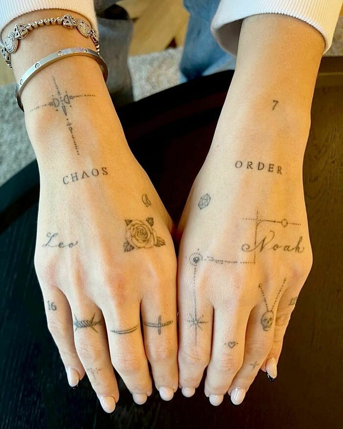 two people with tattoos on their hands holding each other's hands and the word chaos written in cursive writing