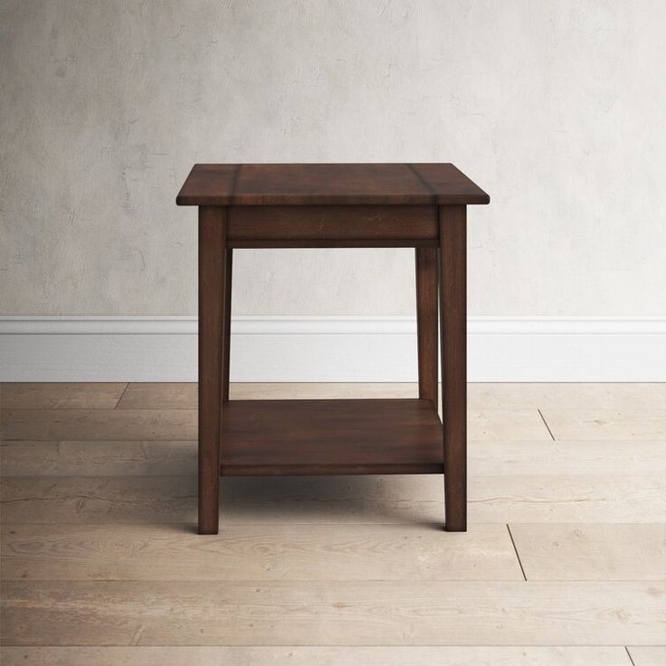 a small wooden table sitting on top of a hard wood floor next to a white wall