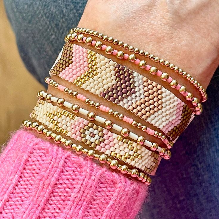 a close up of a person's arm wearing different bracelets and rings on it