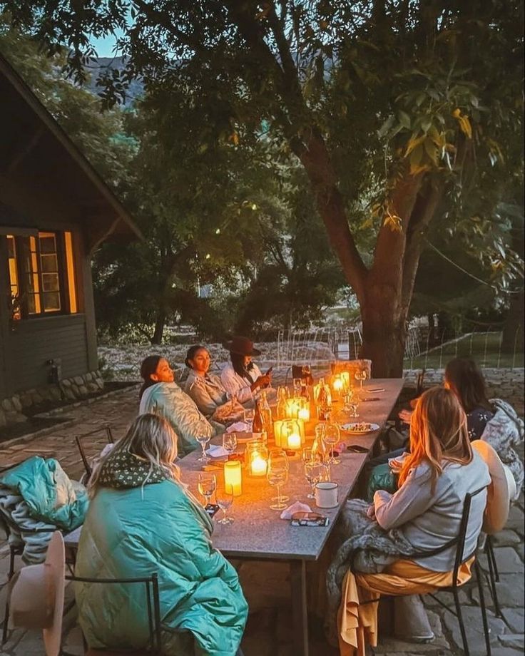 a group of people sitting around a table with candles on it