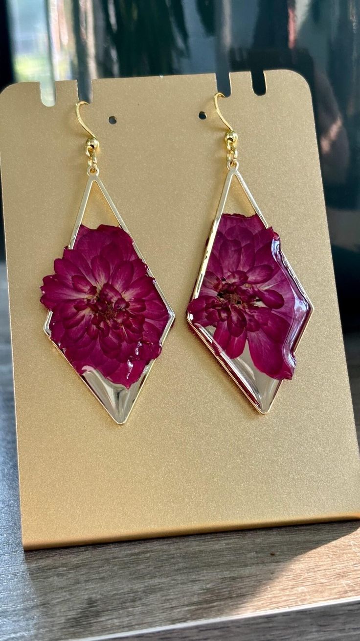 a pair of pink flower earrings sitting on top of a table