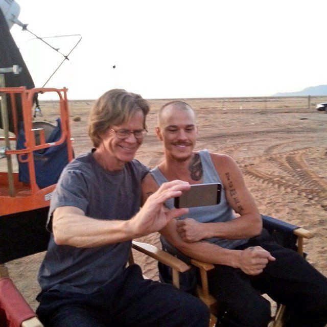 two men sitting on chairs in front of a truck and one man is holding an electronic device