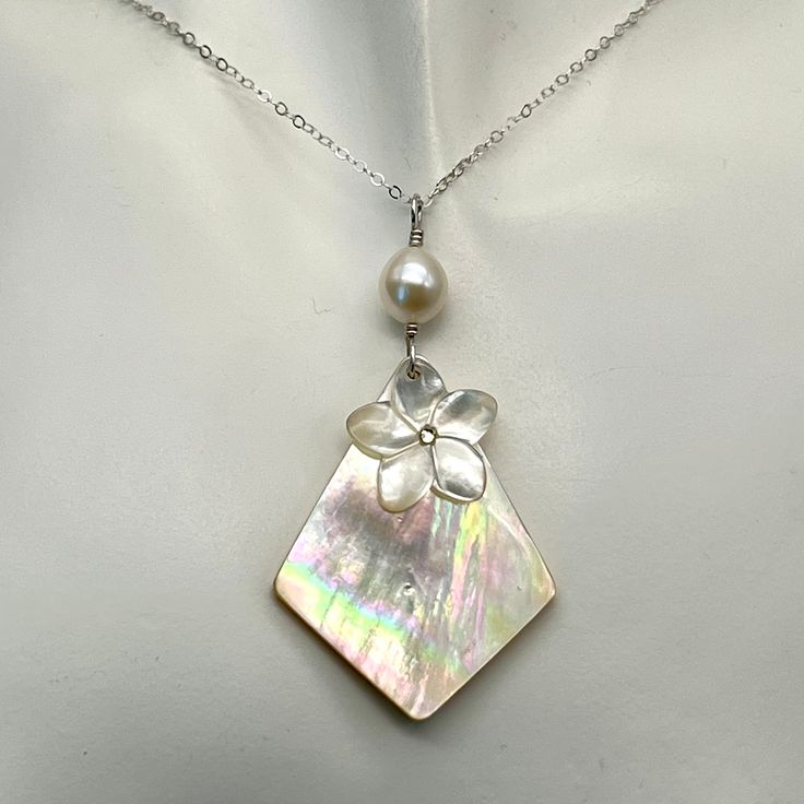 This yellow mother of pearl diamond shaped pendant has gorgeous tones of pinks, purples and light greens. Sadly it is the only one I have. It is topped with a carved mother of pearl plumeria with a small Swarovski yellow crystal in the center. A lustrous oval freshwater pearl tops this pendant. It is about 2 1/4 inches from the top of the sterling silver wire wrap to the bottom of the pendant. The necklace can come in many lengths. If you don't see a length you need please message me. To see mor Pearl White Mother Of Pearl Shell Necklace Gift, Pearl White Mother Of Pearl Shell Necklace As Gift, White Mother Of Pearl Pendant Shell Necklace, Unique Mother Of Pearl Jewelry With Pearl Pendant, Unique Mother Of Pearl Shell Necklace Gift, Shell-shaped Mother Of Pearl For Jewelry Making, Elegant Mother Of Pearl Shell Pendant Necklace, Artisan Shell-shaped Mother Of Pearl Jewelry, Artisan Mother Of Pearl Shell Jewelry