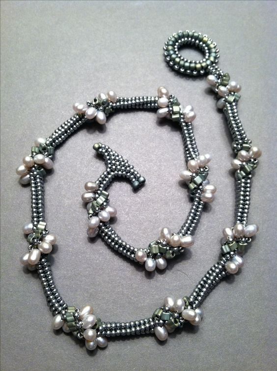 a necklace and bracelet made out of silver beads with white pearls on the clasps