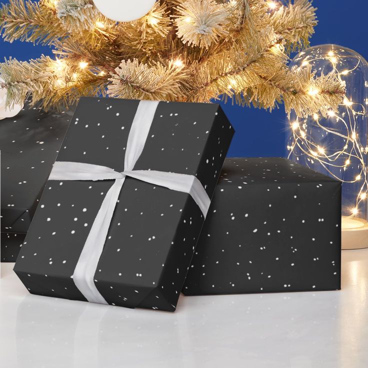 two wrapped presents under a christmas tree with lights on the branches in front of it