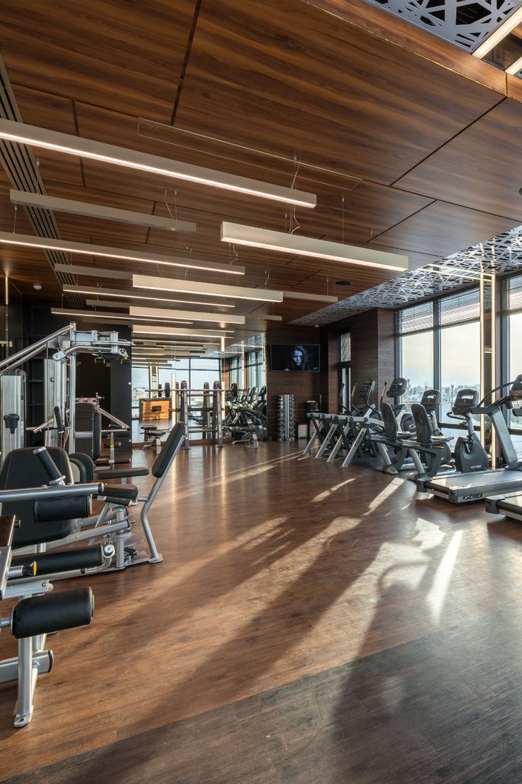 an empty gym with lots of machines and windows overlooking the cityscape is seen in this image