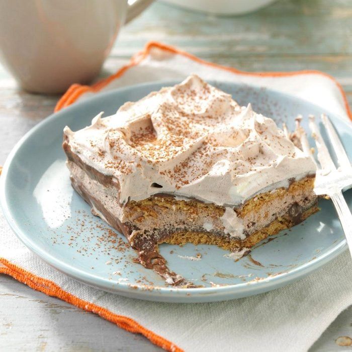 a piece of cake on a plate with a fork next to it and a cup in the background