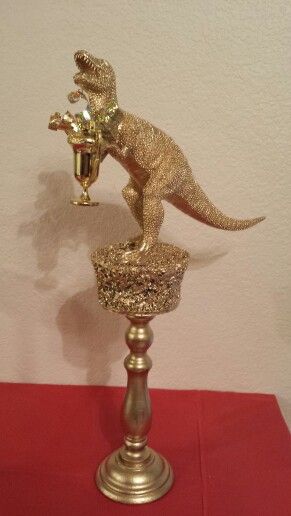 a gold colored dinosaur figurine sitting on top of a red table