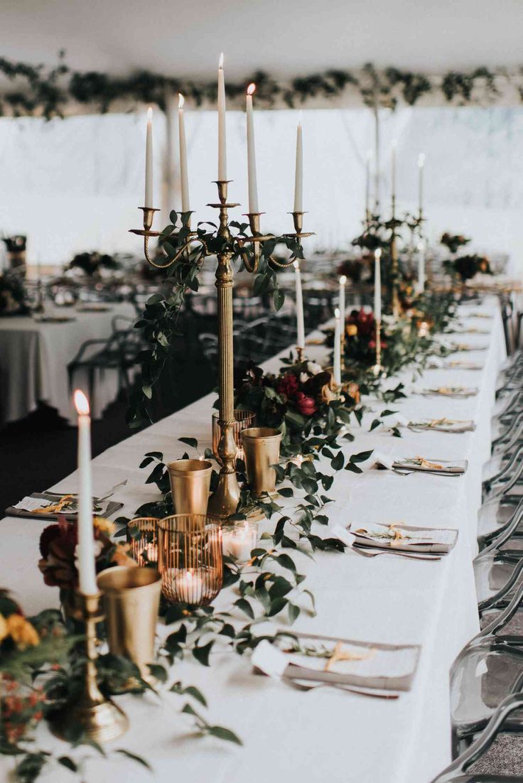 a long table with candles and greenery on it is set up for an event