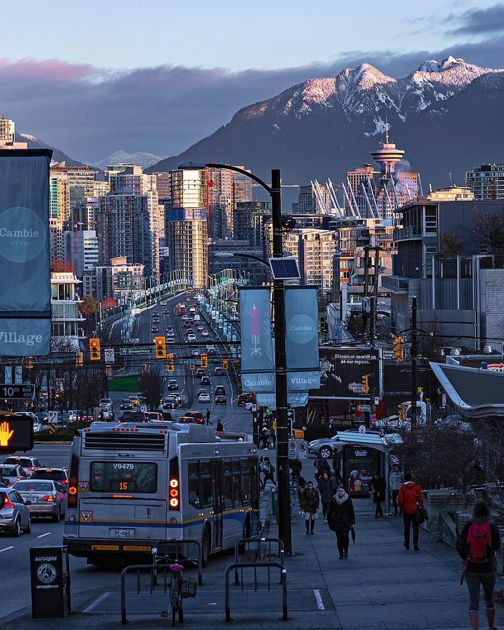 a busy city street with lots of traffic and tall buildings in the background at dusk