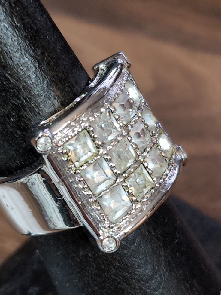 a diamond ring is sitting on top of a black piece of leather with a wooden surface in the background