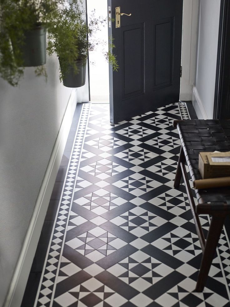 a black and white tiled hallway with potted plants