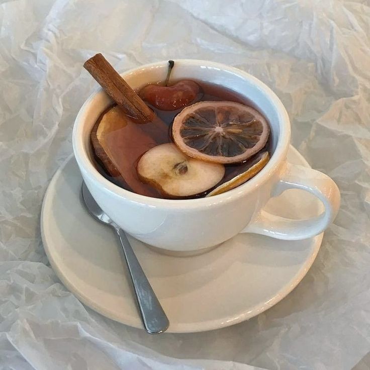 a cup filled with fruit and cinnamon on top of a white plate