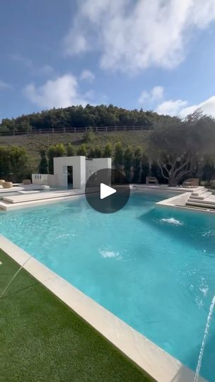 an outdoor swimming pool with artificial grass around it and water spouting from the side