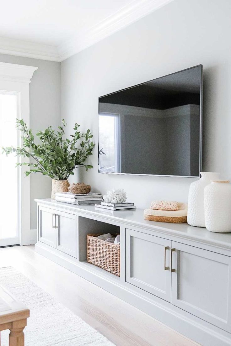 a living room with white furniture and a large flat screen tv mounted on the wall