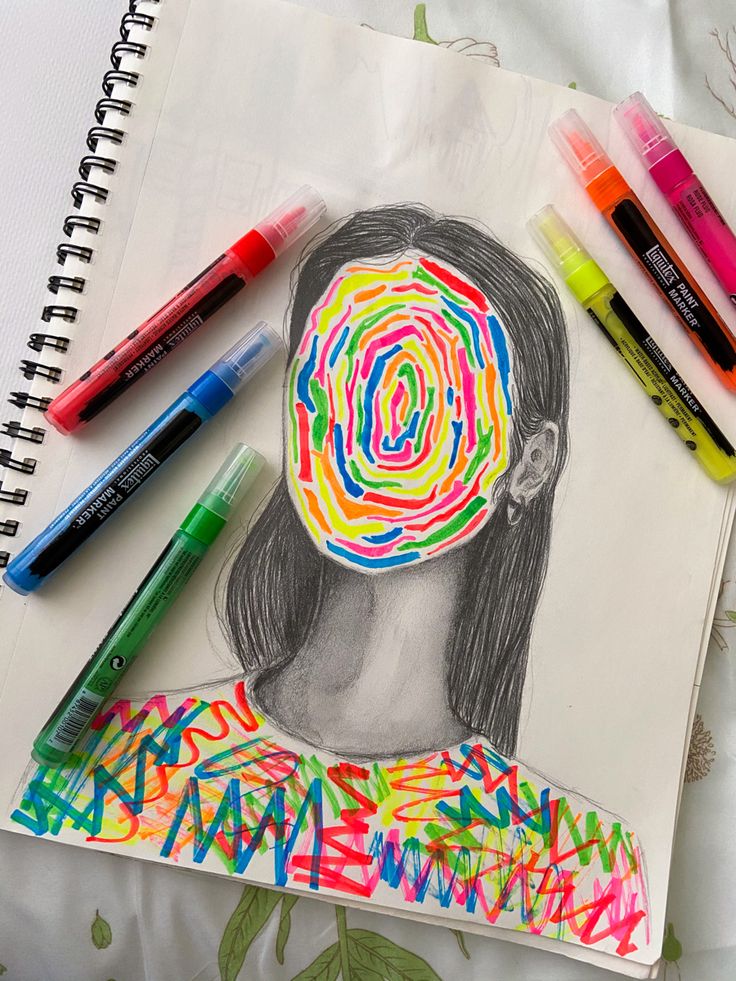 a drawing of a person's head is surrounded by markers and crayons