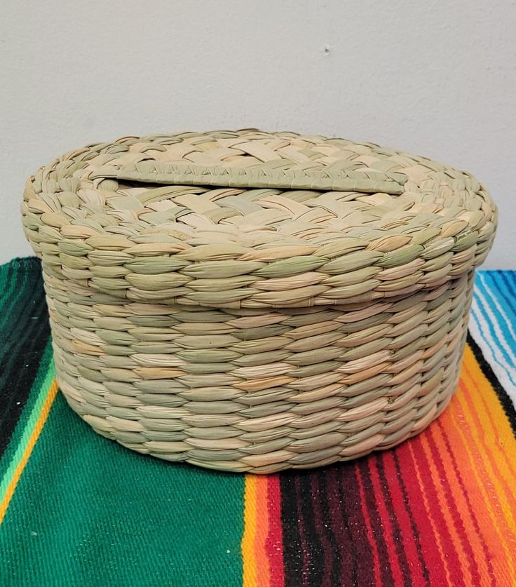 a woven basket sitting on top of a colorful blanket