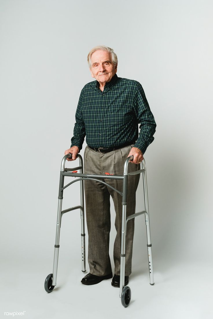 an older man with a walker standing in front of a white background