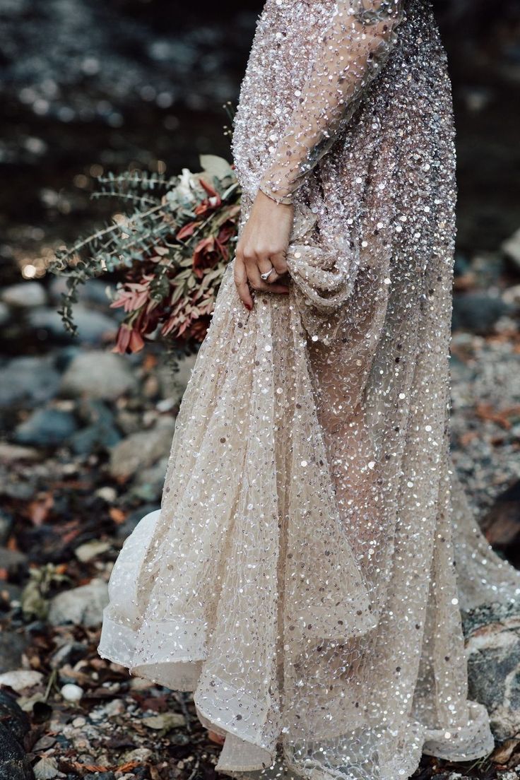 a woman in a long dress standing on rocks