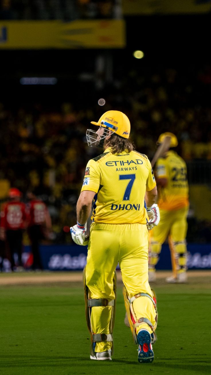 a man standing on top of a green field wearing yellow and white uniform with his hands in his pockets