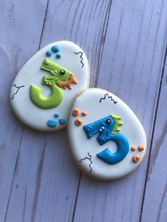 two decorated cookies sitting on top of a white wooden table with letters and numbers painted on them