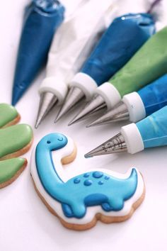 cookies decorated with icing and markers are arranged in the shape of dinosaurs on a white surface