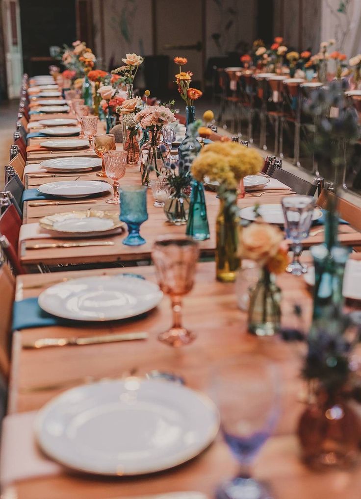 a long table with plates and vases filled with flowers on top of each plate