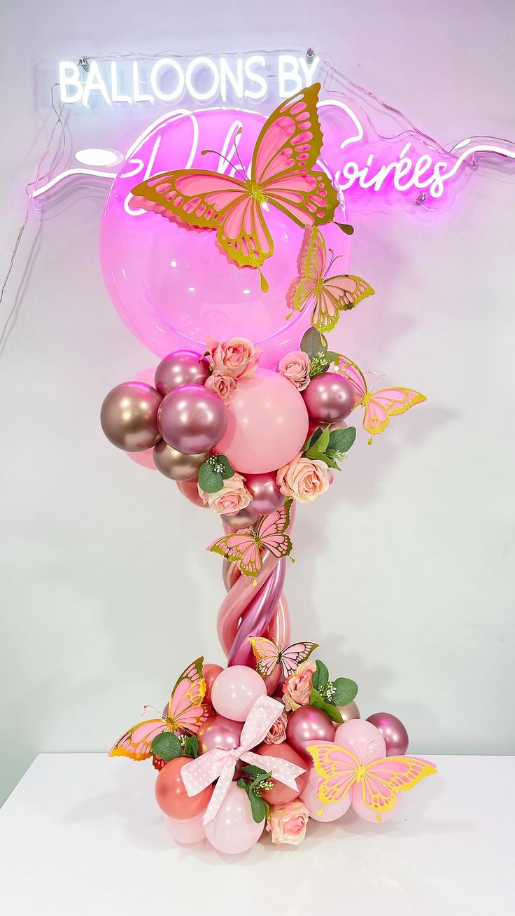 balloon sculpture with pink and gold balloons in the shape of a butterfly on top of it