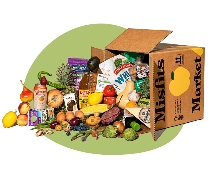 an open cardboard box filled with assorted fruits and veggies on a green background