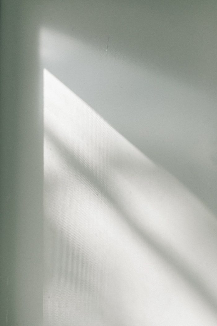 a black and white photo of the corner of a room with sunlight coming in through the window