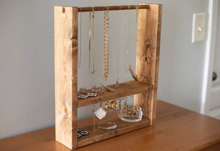 a wooden frame with jewelry hanging from it's sides on a table next to a door