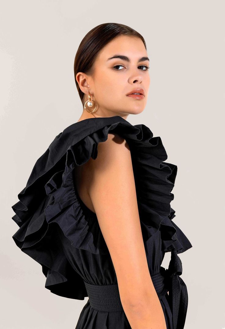 a woman is wearing a black dress with ruffles on the shoulders and back