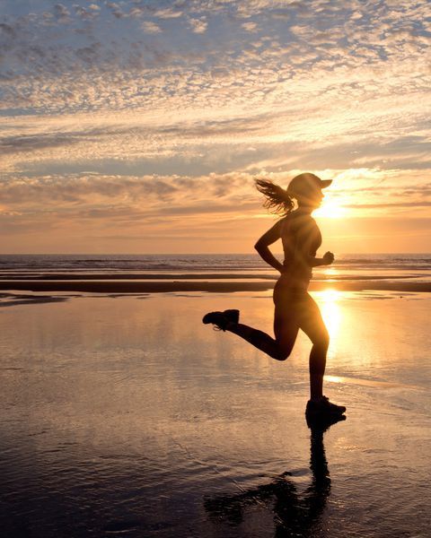 a woman running on the beach at sunset