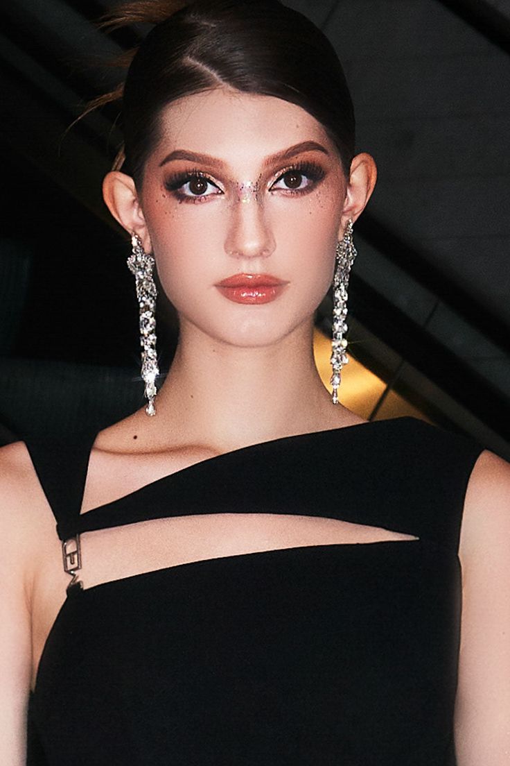 a woman in a black dress with large earrings