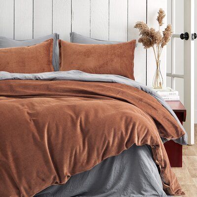 a bed with brown and grey sheets in a bedroom