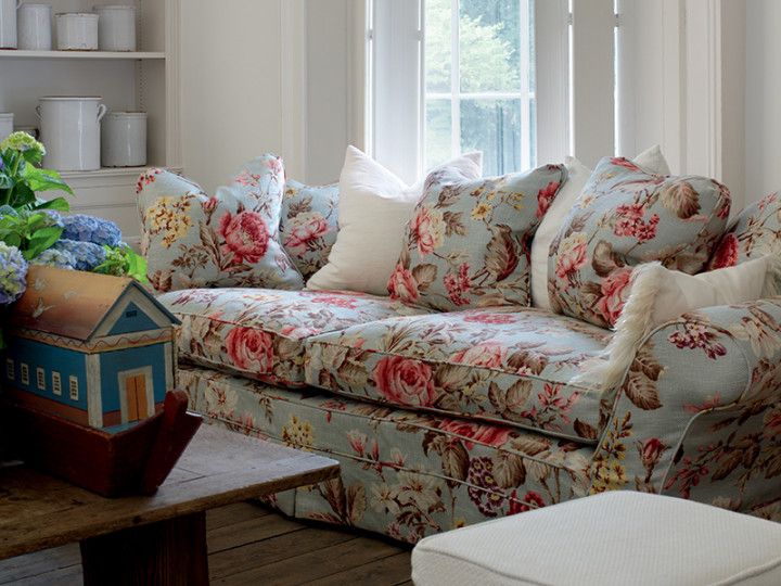 a living room filled with lots of furniture and flowers on top of the couches