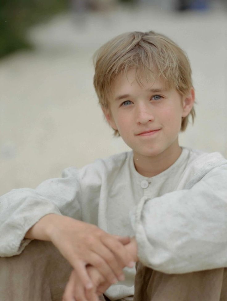 a young boy sitting on the ground with his arms crossed