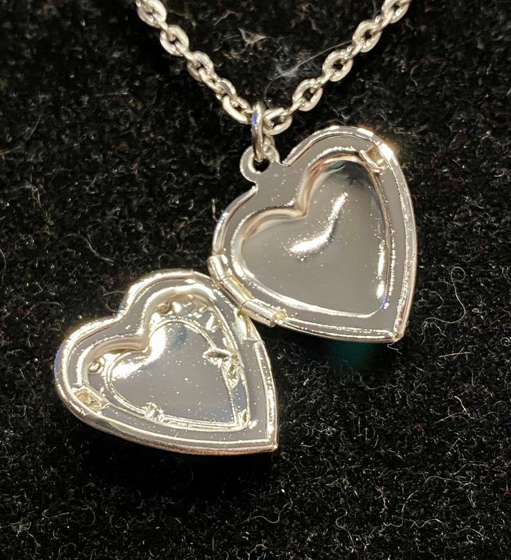 Necklace is silver in color Measures 18 inches in length Pendant measures 1 inch in length and width Silver Heart-shaped Metal Jewelry, Silver Heart Shaped Metal Jewelry, Heart Shaped Silver Metal Jewelry, Silver Heart Necklace With Round Pendant For Anniversary, Silver Metal Charm Necklaces For Valentine's Day, Heart Pendant Metal Locket Necklace For Keepsake, Adjustable Silver Heart Jewelry, Silver Charm Necklaces For Valentine's Day, Heart Pendant Locket Necklace As Keepsake