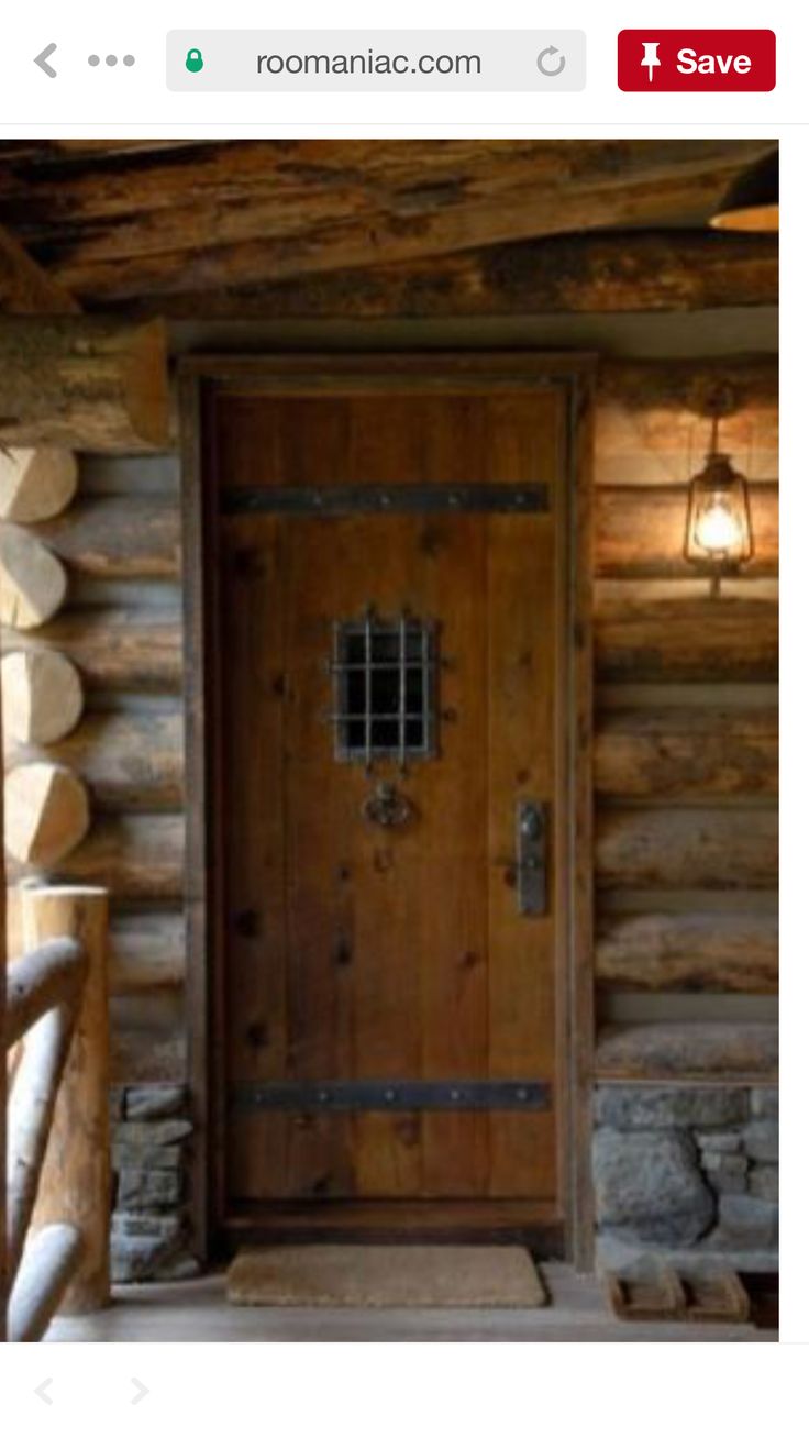 a wooden door in a log cabin with lights on the wall and wood flooring