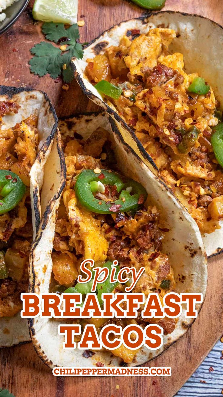 three breakfast tacos on a wooden board with limes and jalapenos