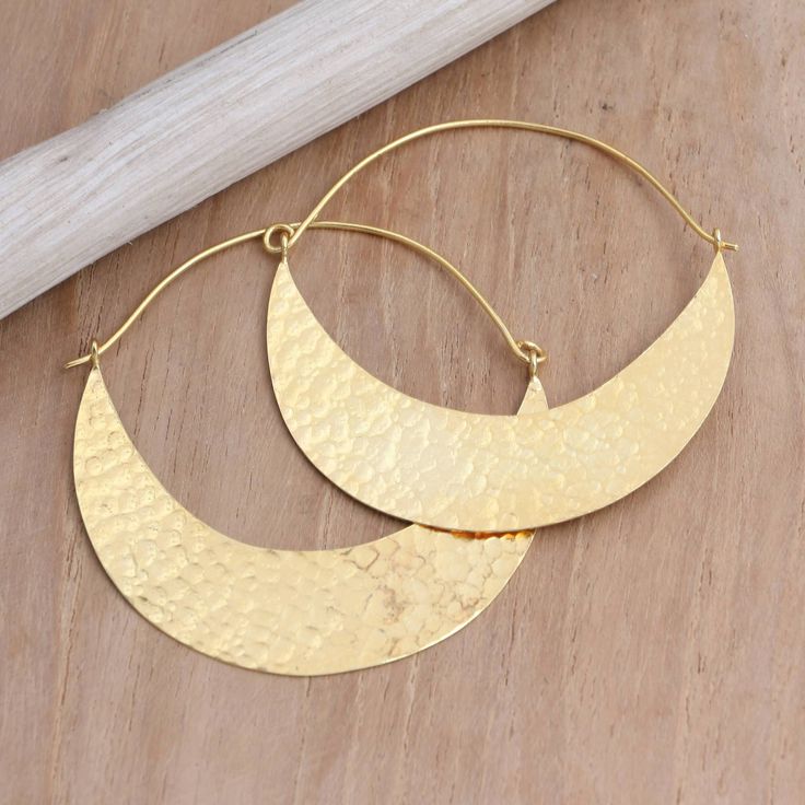 Glamorous and sophisticated, Wayan Karang's hoop earrings are carefully designed with semi-circles of shimmering gold resembling a canoe. Balinese artisans use 22k gold-plated brass to hand craft the earrings, treating the precious metal with a unique hammered finish. Handmade Semi-circle Gold Jewelry, Gold Semi-circle Brass Jewelry, Gold Crescent Hoop Earrings With Ear Wire, Gold Crescent Hoop Earrings In Brass, Gold Crescent Hammered Earrings, Gold Hammered Crescent Earrings, Elegant Gold Half Moon Hoop Earrings, Elegant Half Moon Gold Hoop Earrings, Gold Semi-circle Brass Earrings