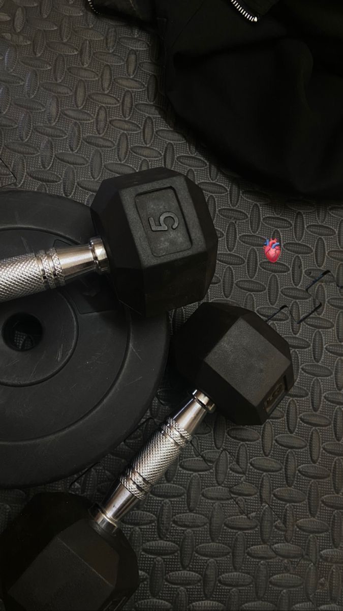 two black dumbbells sitting next to each other on a gray carpeted floor