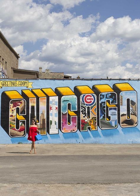 a woman walking in front of a wall with the word chicago painted on it