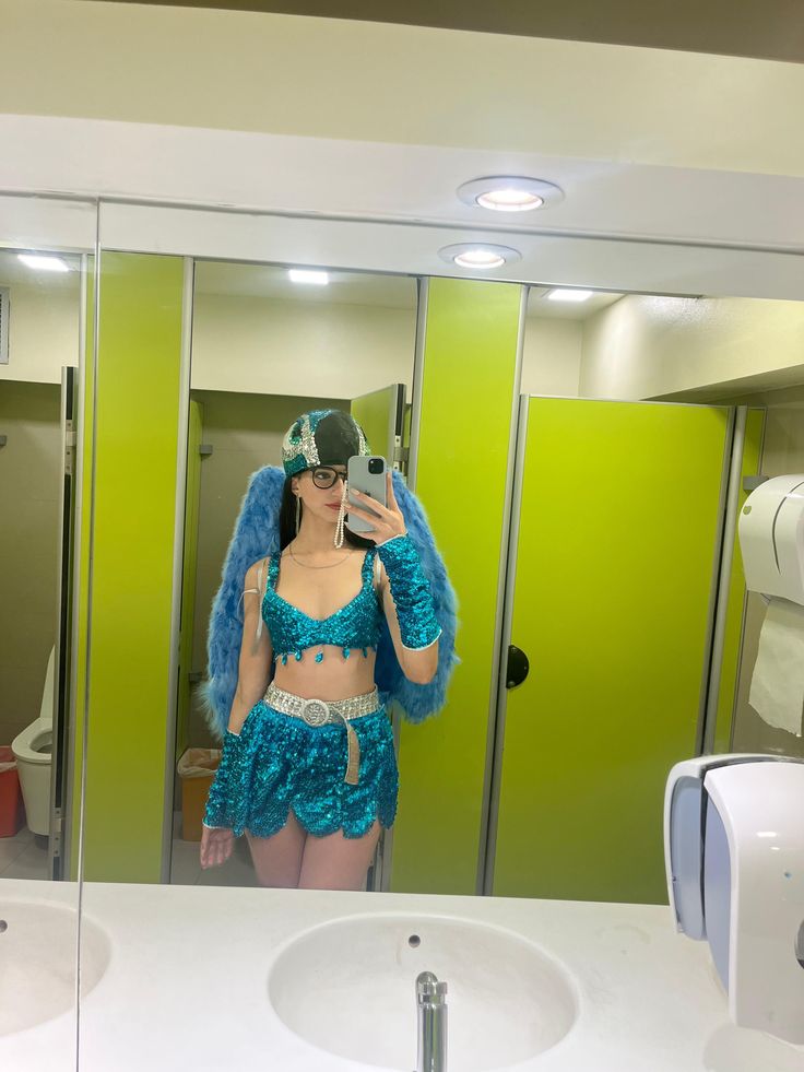 a woman taking a selfie in front of a bathroom mirror wearing a blue costume