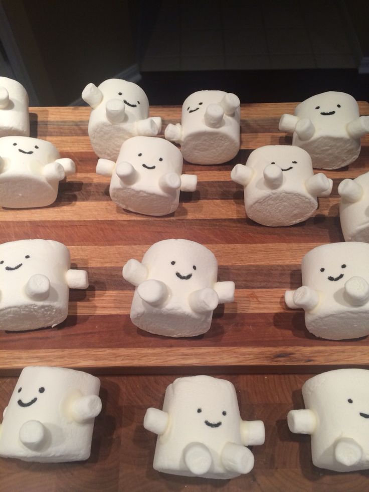 many white marshmallows are arranged on a wooden board with faces and arms