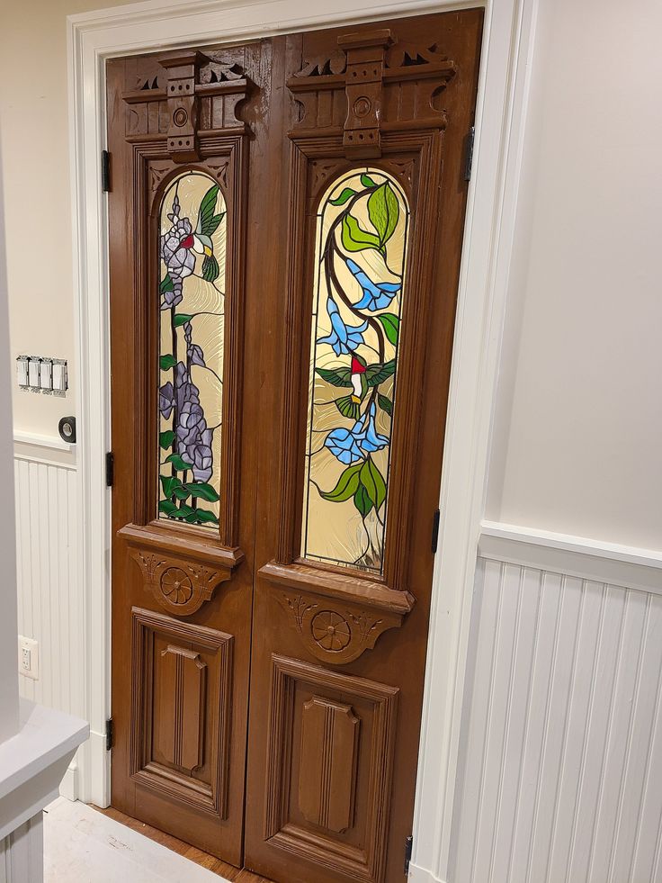 two stained glass doors in the entryway to a home with white walls and wood trimming