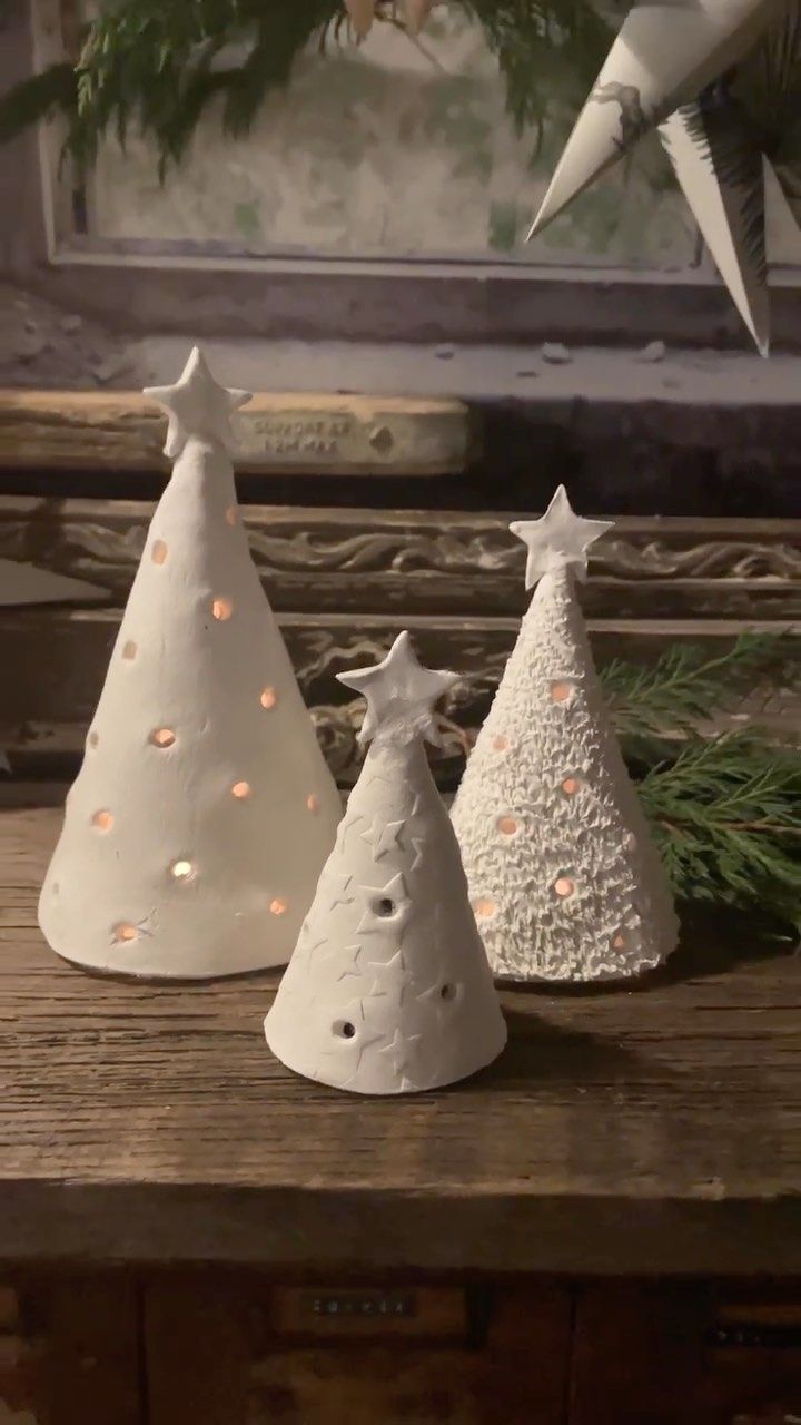 three ceramic christmas trees sitting on top of a wooden table